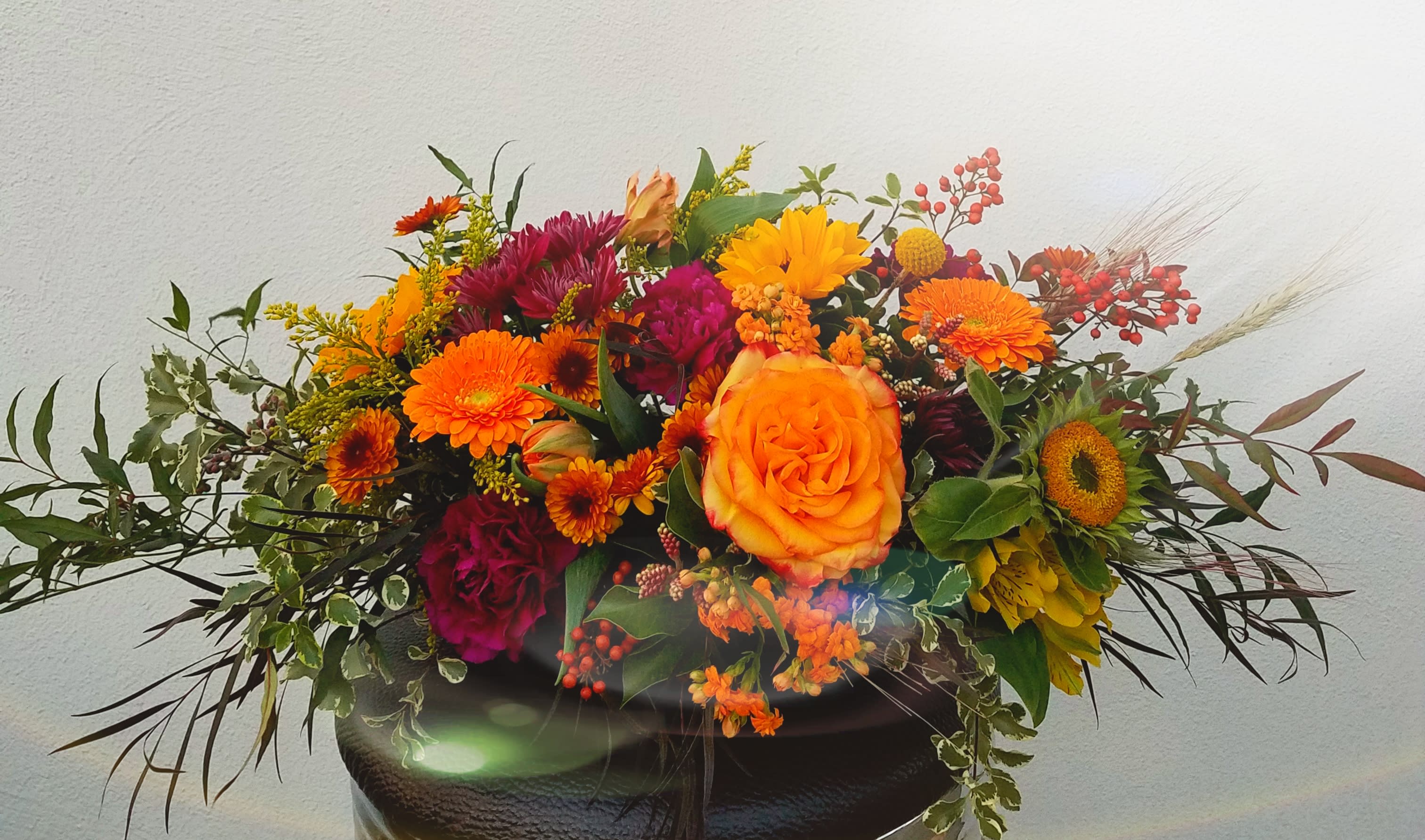 Bright mixed bouquet with orange and magenta flowers in a dark vase
