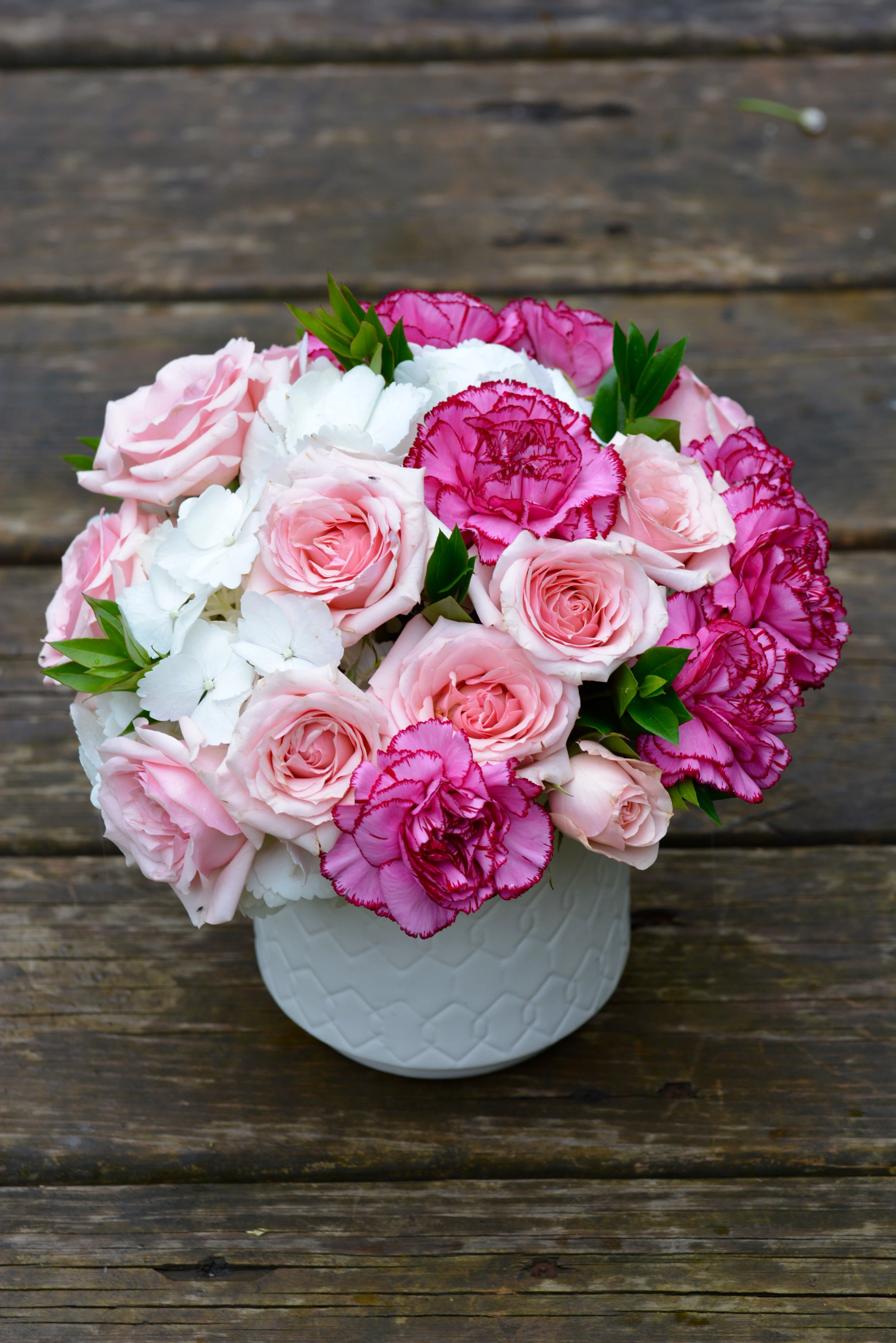 Pink roses and magenta carnations in a white vase