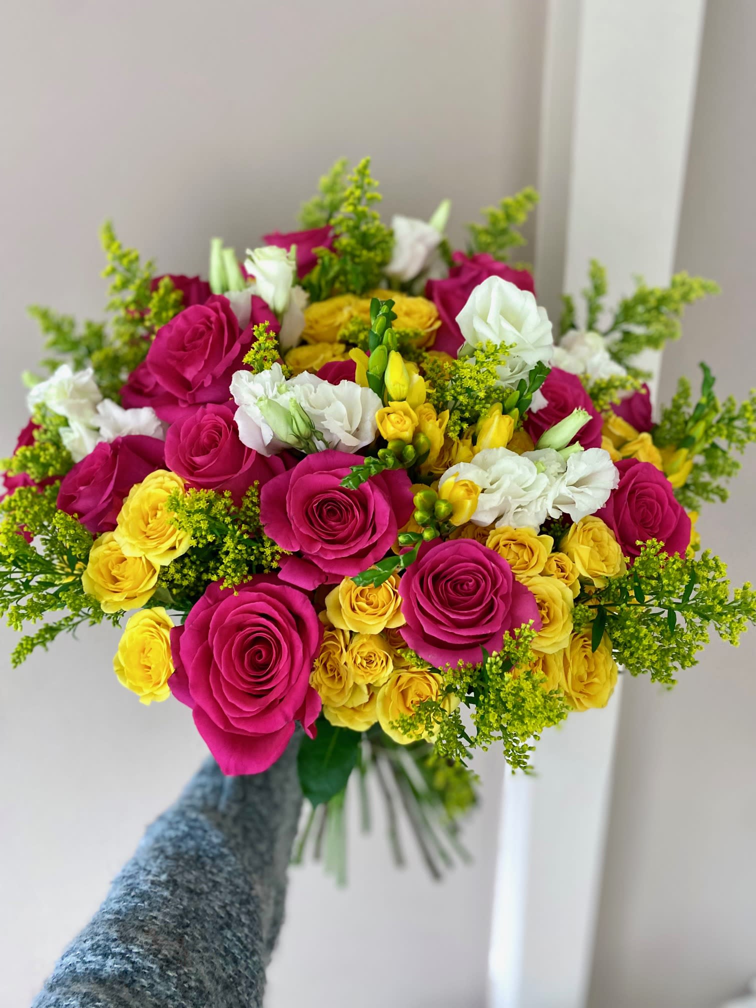 Handheld bouquet of pink, yellow, and white roses