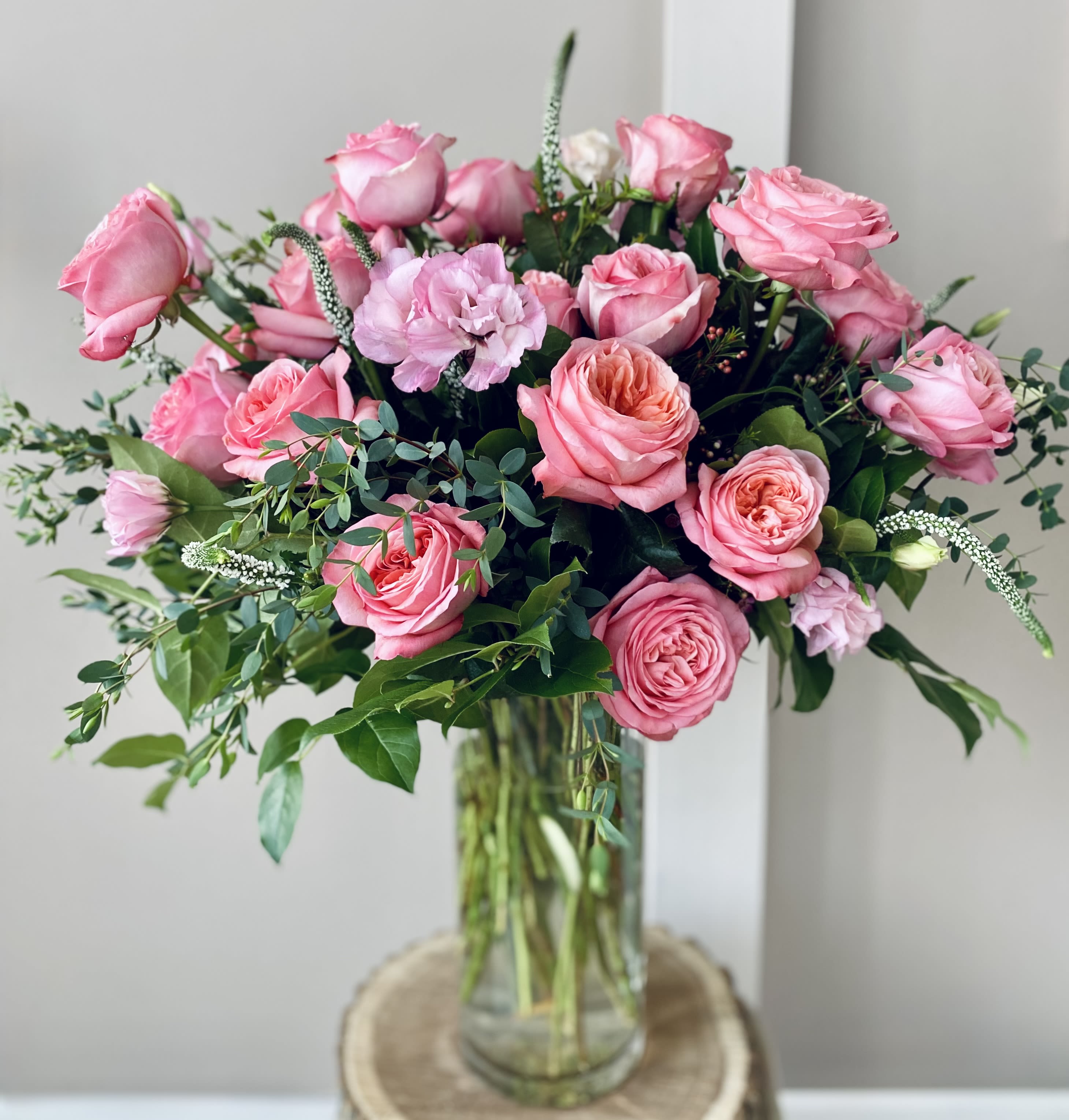 Pink roses arranged in a clear glass vase with greenery