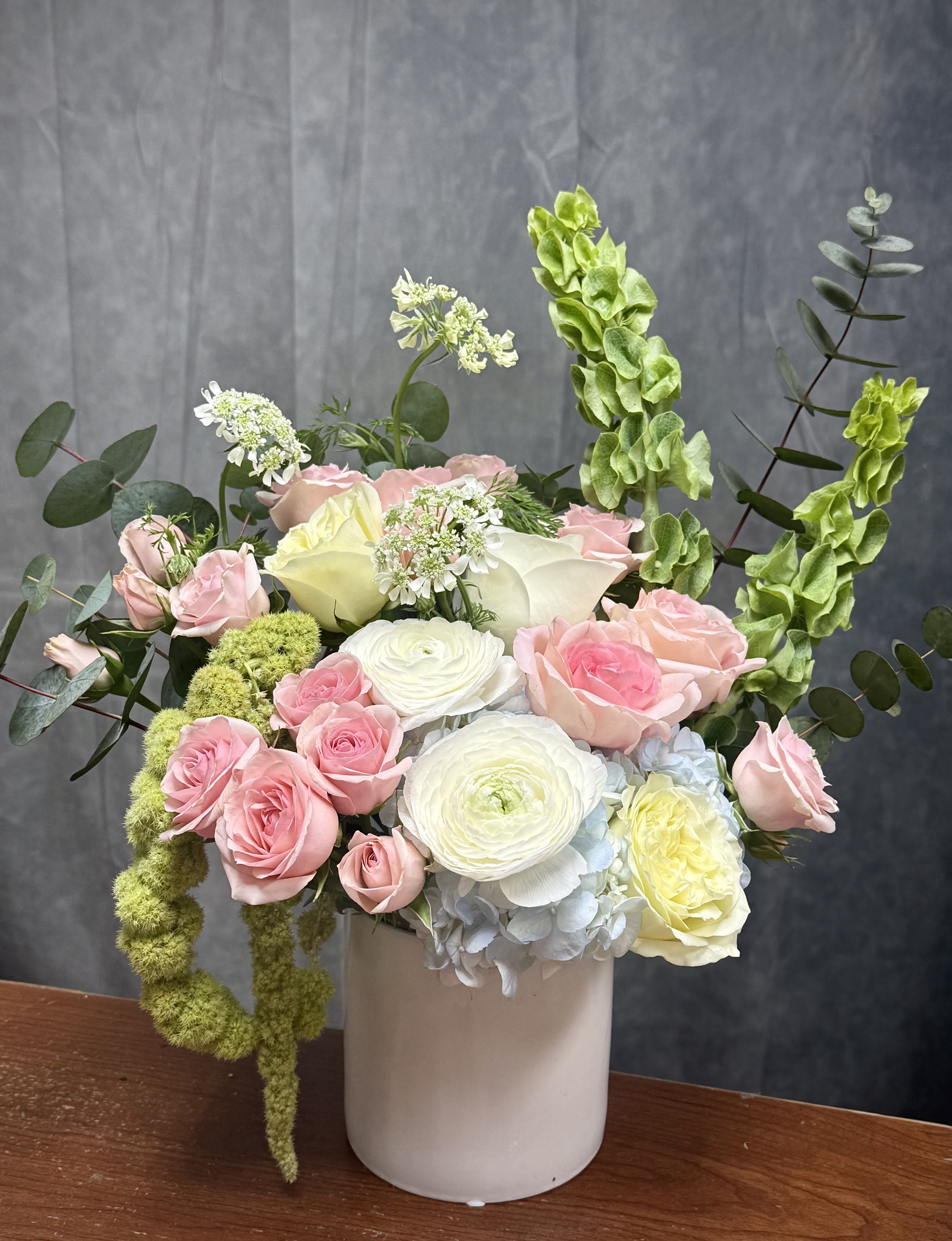 Pink and white roses with ranunculus in a white vase