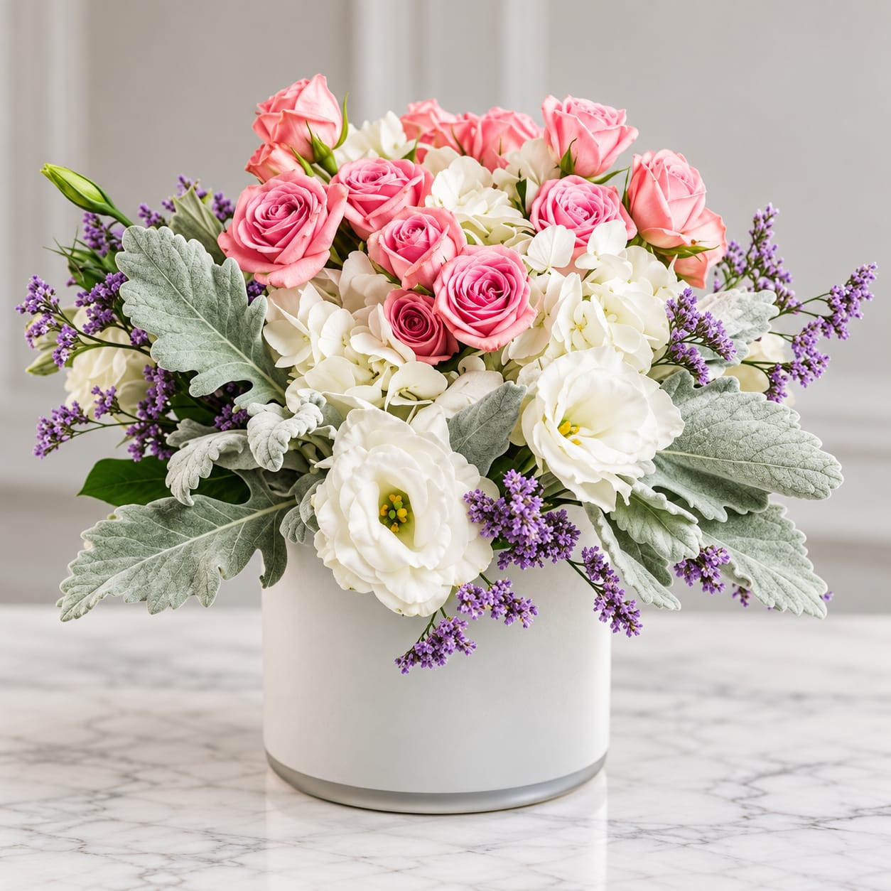 Pink roses and white blooms arranged in a white vase with purple accents