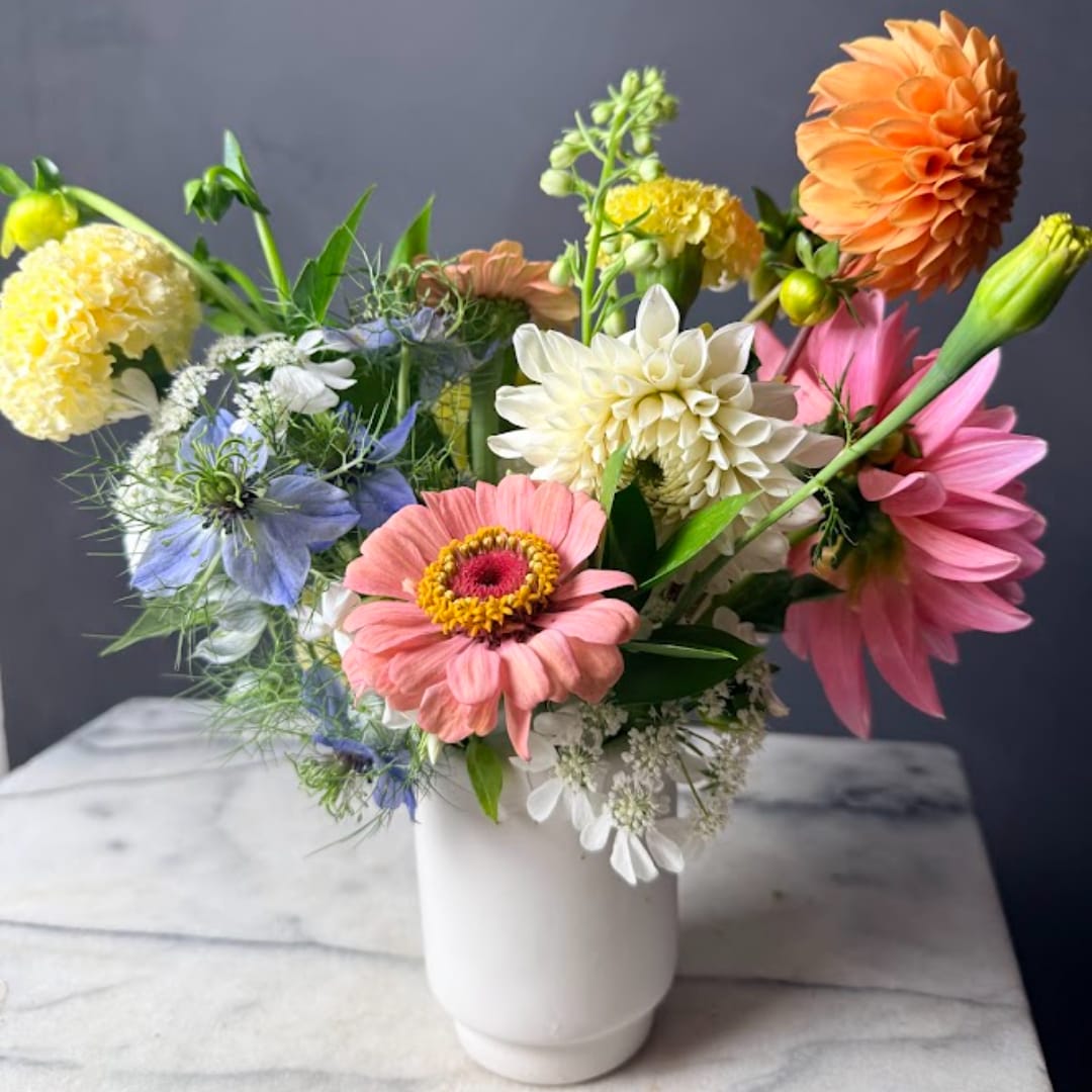 Mixed bouquet of colorful flowers in a white vase
