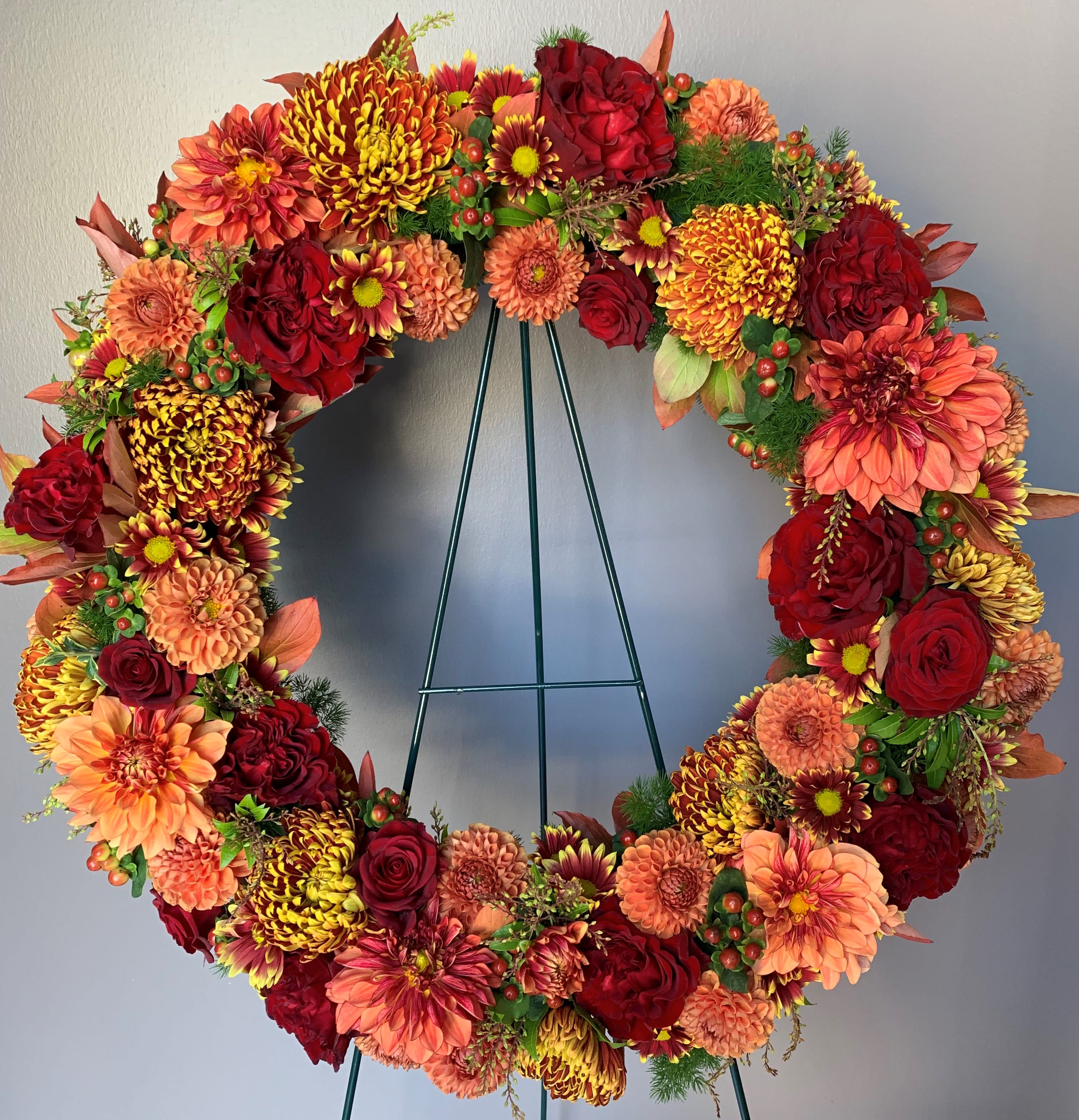Autumn Tribute Wreath - Rich and robust. This beautiful tribute wreath is made up of a rich mix of fall favorites such as mums, dahlias, roses, hypericum berries and more.   Please Note: Design may not look exactly like what is pictured. Will vary due to floral availability and artistic interpretation. 