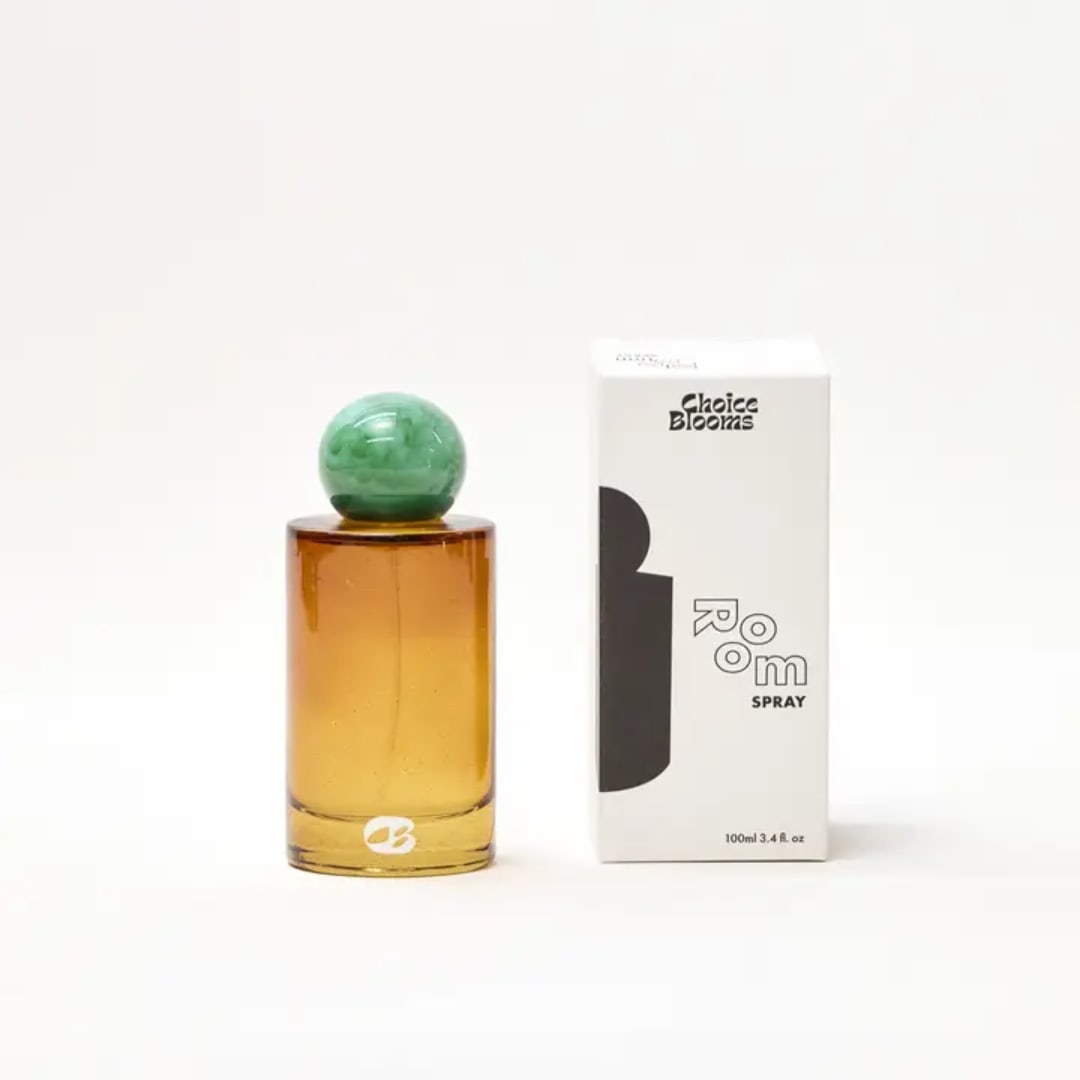 Amber room spray bottle beside its box on a white background