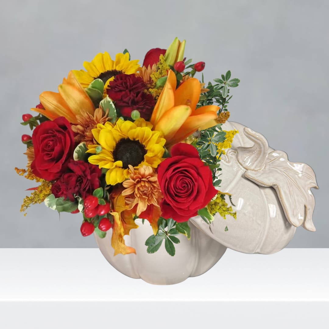 Bouquet of red roses, sunflowers, and orange lilies in a white pumpkin vase