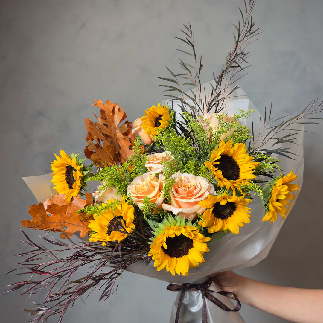 Bouquet of sunflowers and peach roses wrapped in white paper