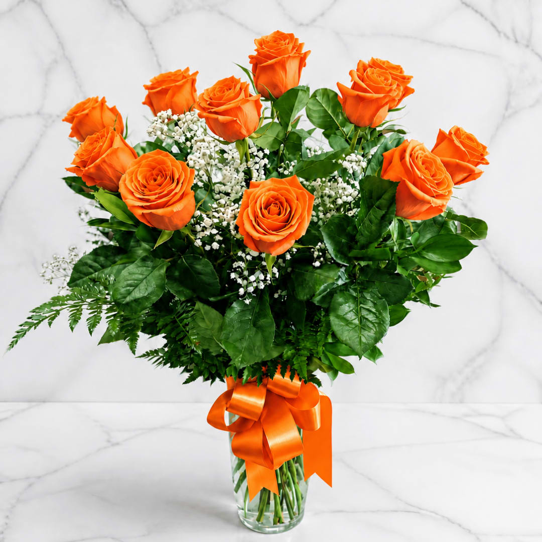Orange roses in a clear glass vase with a ribbon bow