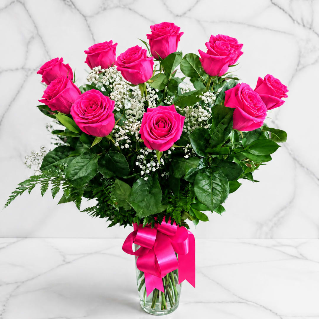 Bouquet of hot pink roses in a clear glass vase with a pink ribbon