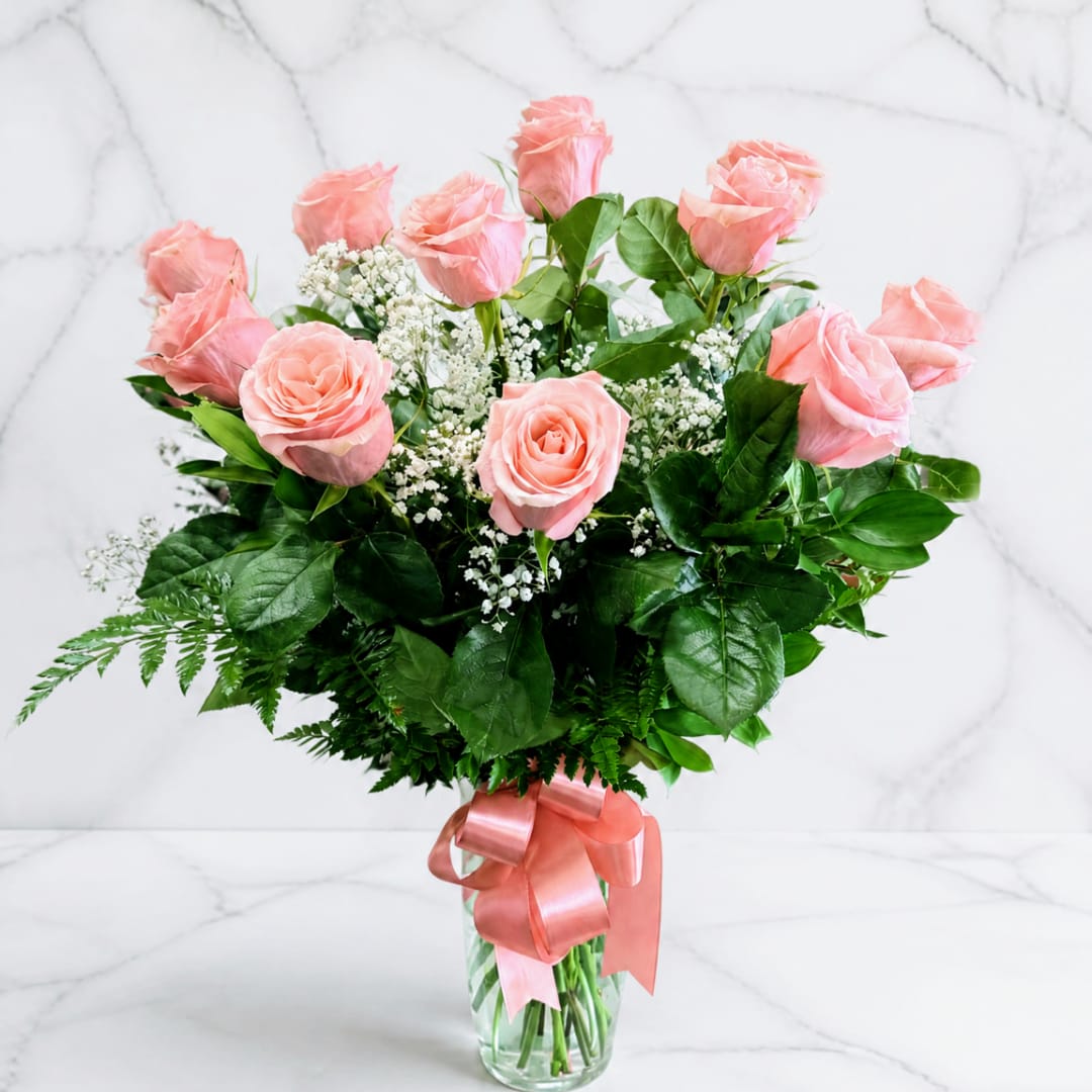 Pink roses in a clear glass vase with a satin ribbon