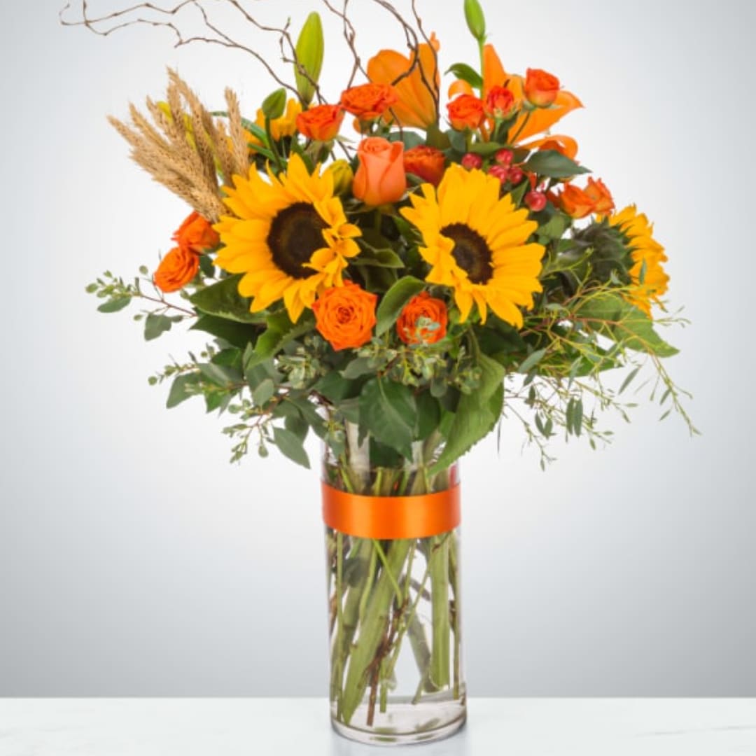 Sunflower and orange rose bouquet in a tall glass vase