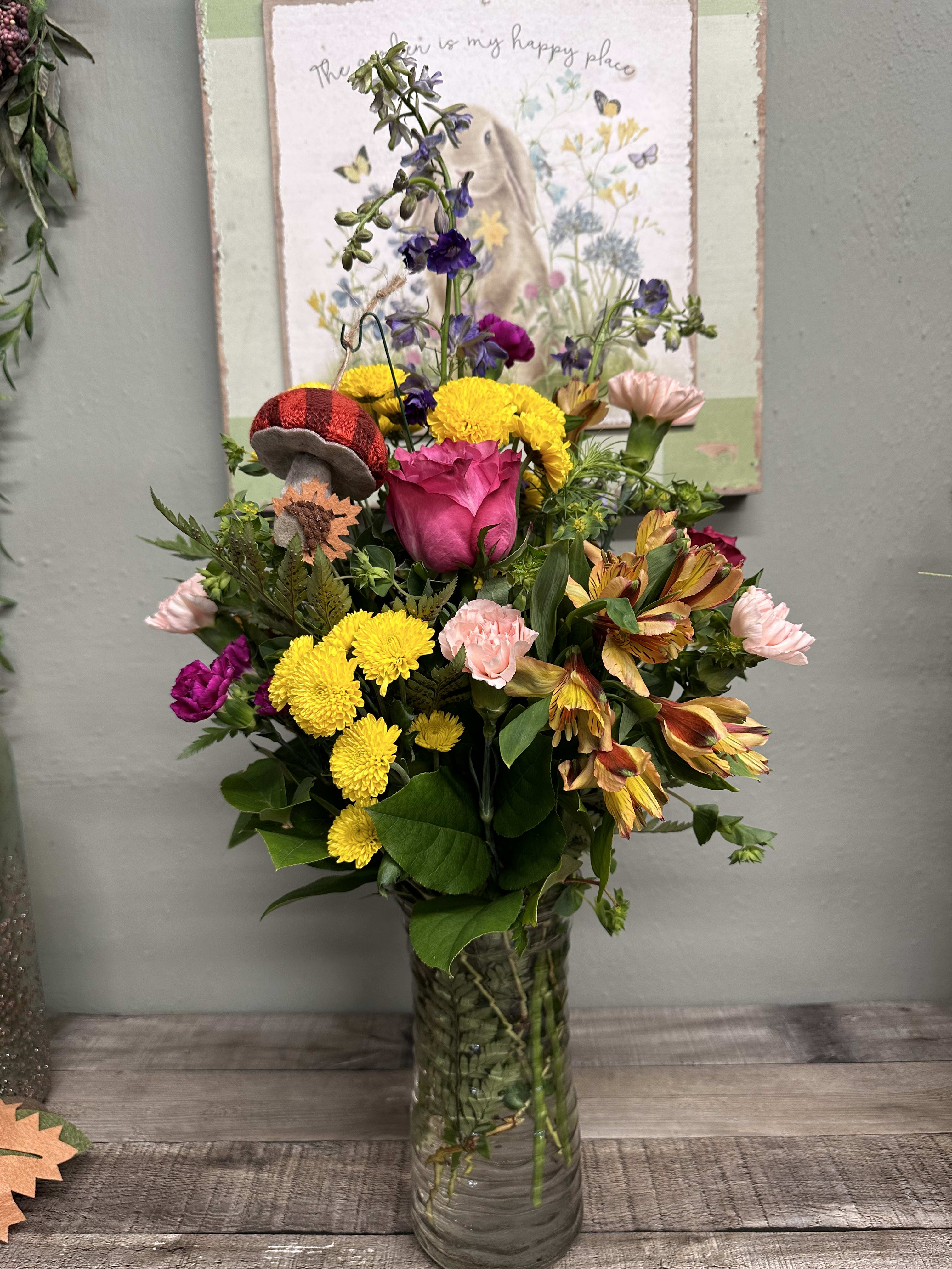 Mixed bouquet in a clear glass vase with pink, yellow, and purple flowers