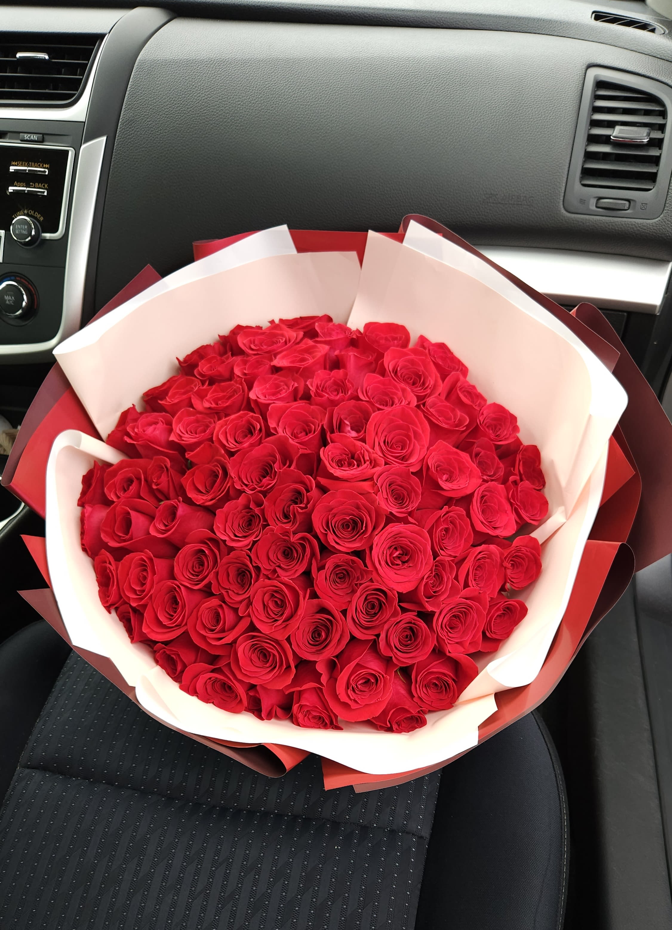 Large bouquet of red roses wrapped in white and red paper