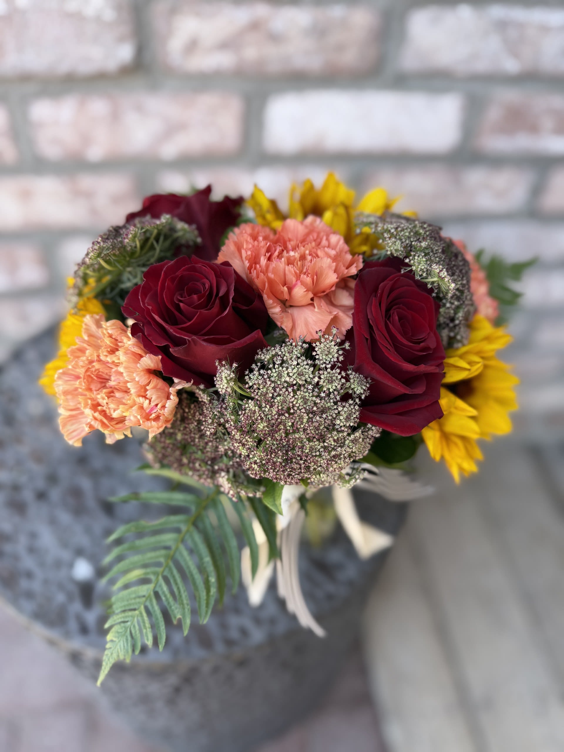 Bouquet of burgundy roses, peach carnations, and yellow flowers
