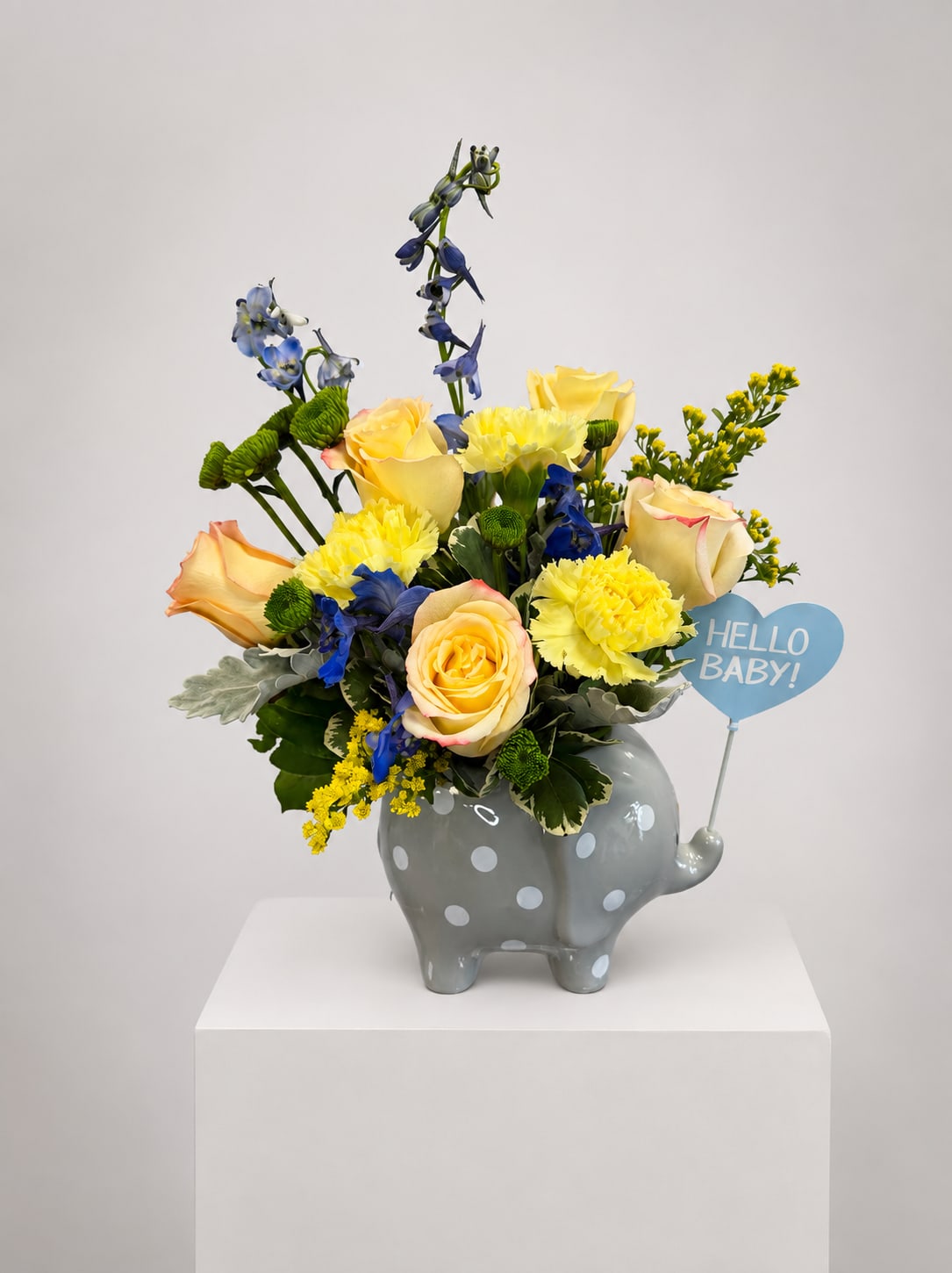 Yellow roses and blue flowers in a gray polka-dot elephant vase with a "Hello Baby!" sign