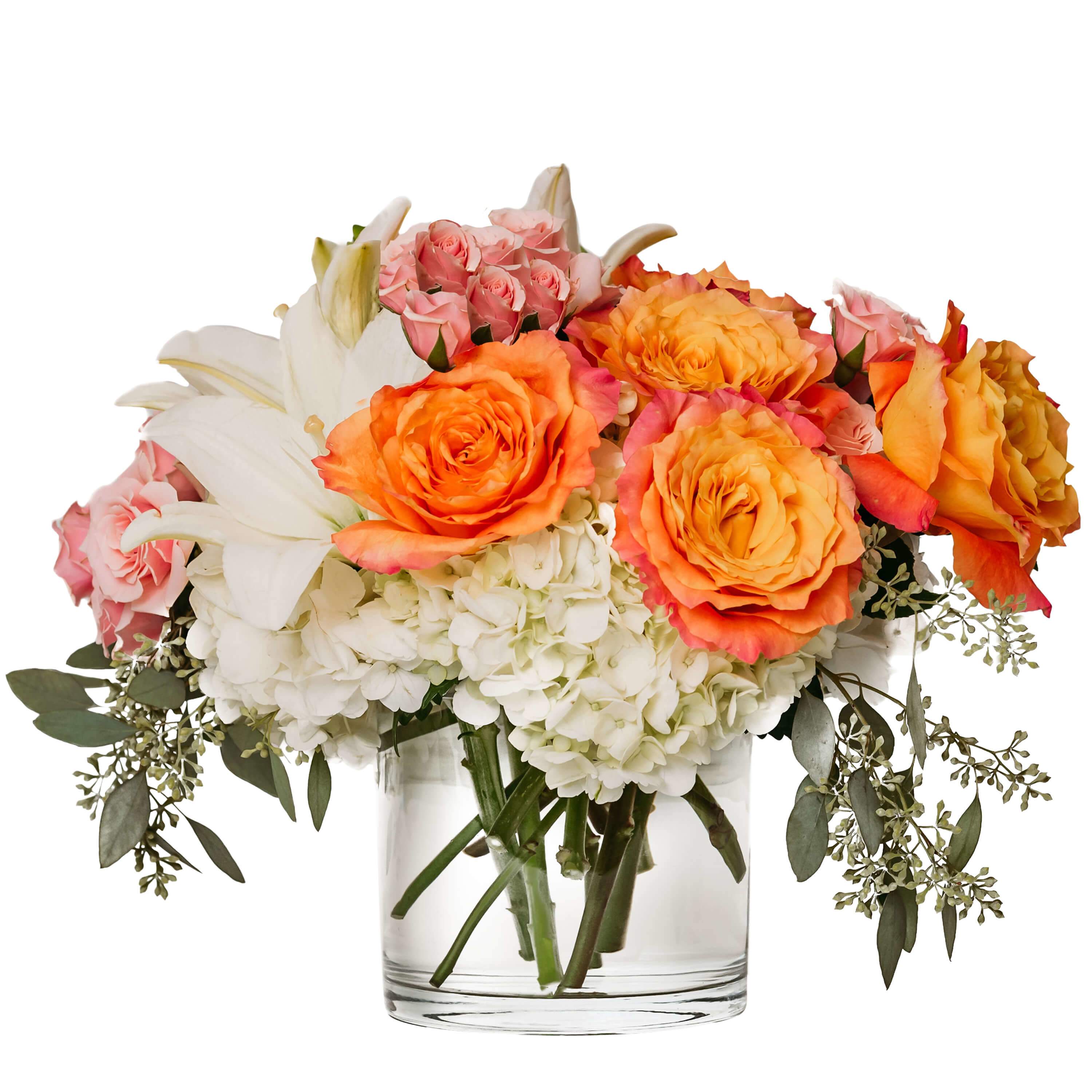 Bouquet of orange and pink roses with white lilies and hydrangeas in a clear glass vase