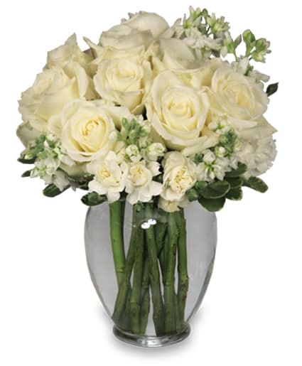 Round arrangement of white roses and white flowers in a clear glass vase