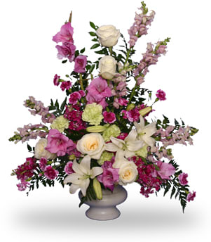 Tall pink, white, and green flower arrangement with lilies and roses in a white pedestal vase