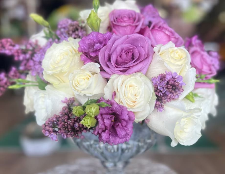Purple and white roses arranged in a glass vase