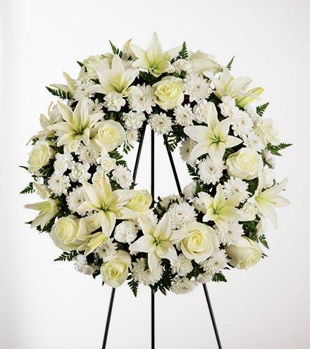 White floral wreath on a black easel stand