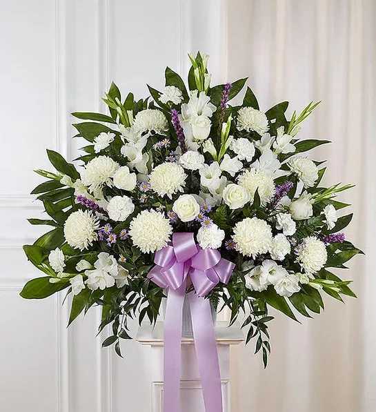 White floral standing spray with a lavender ribbon on a pedestal