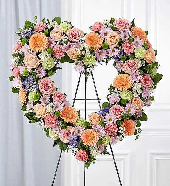 Heart-shaped floral wreath on an easel with pink, peach, and lavender flowers