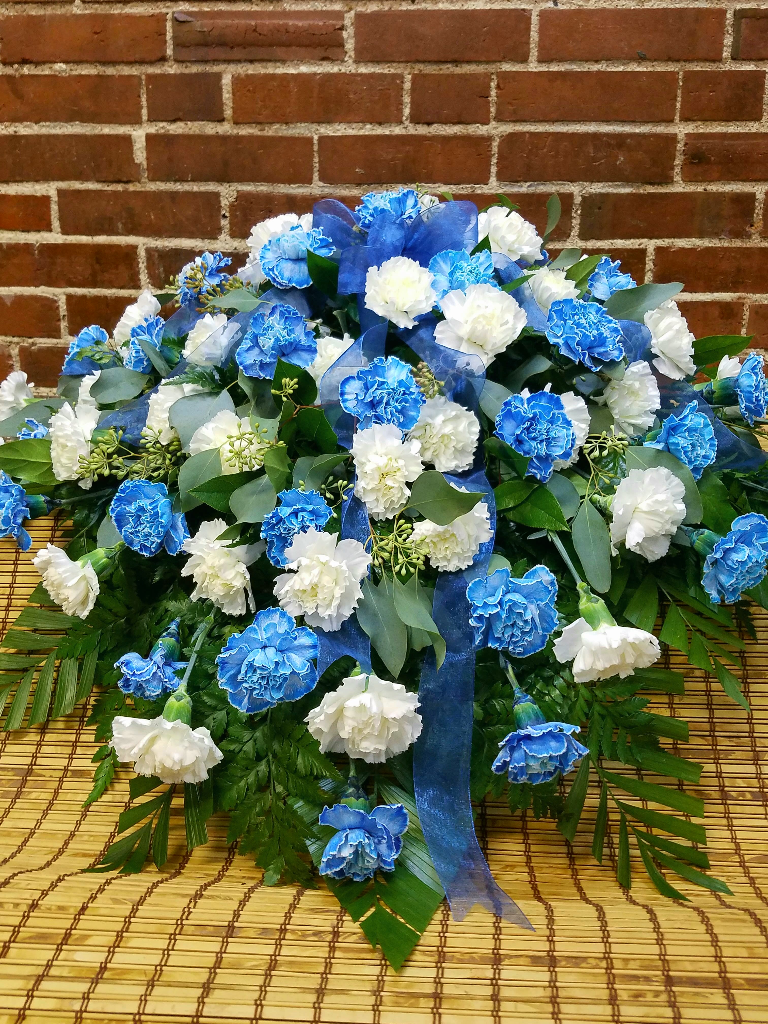 Blue and white carnation arrangement with ribbon on a woven mat