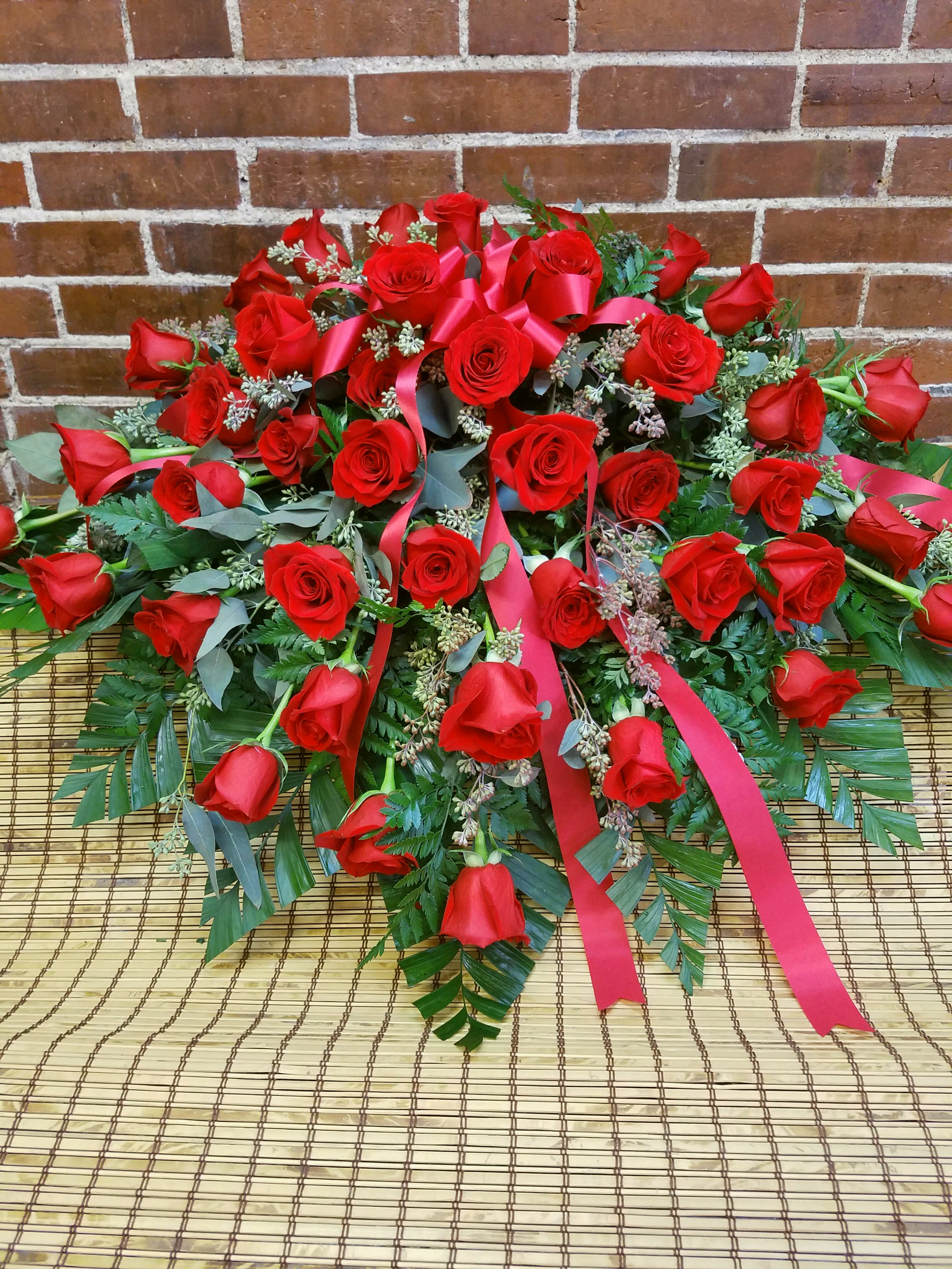 Large arrangement of red roses with pink ribbons