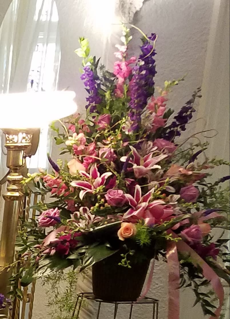 Tall floral arrangement in a black container with pink, purple, and white blooms