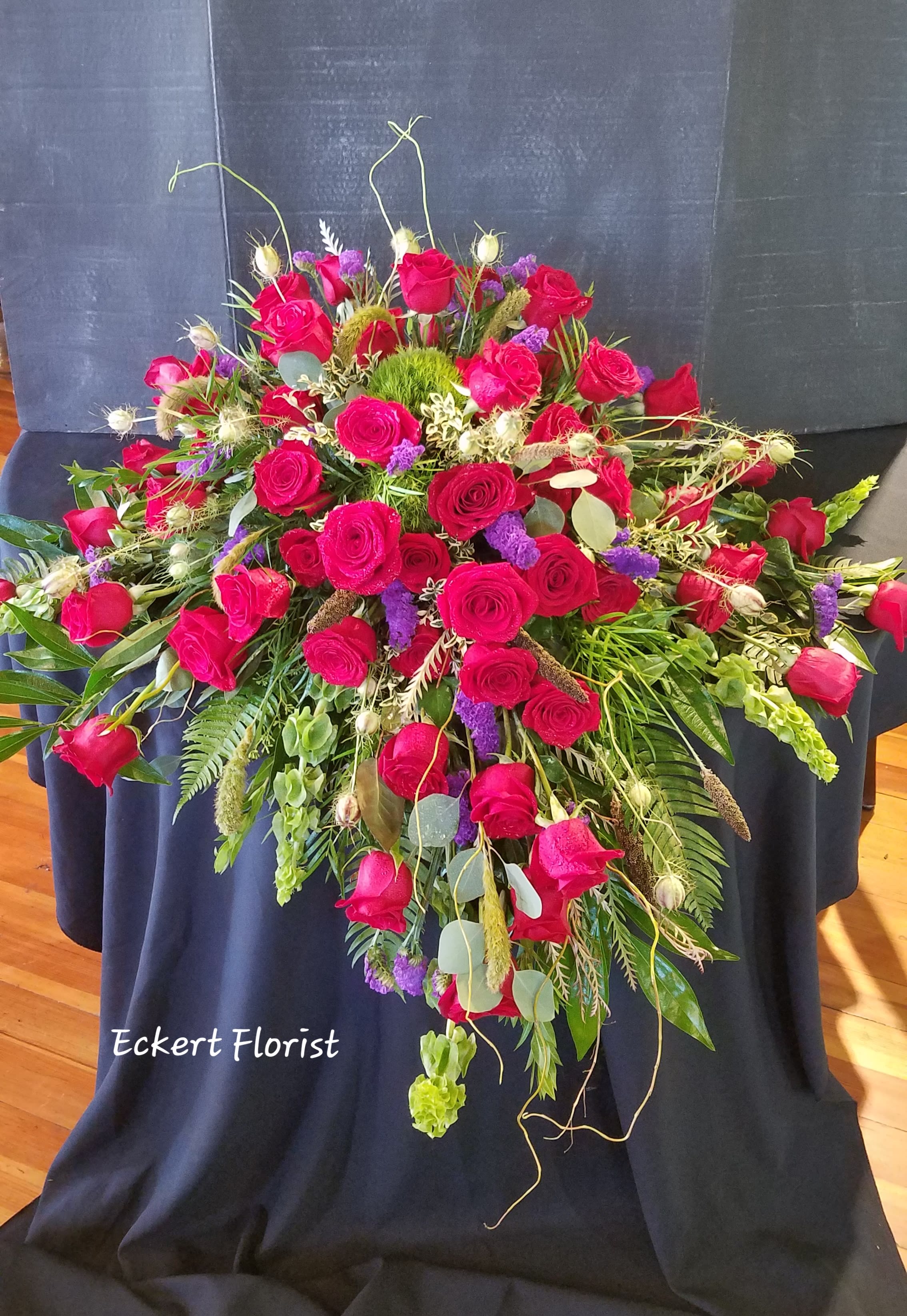 Large red rose arrangement with purple accents and mixed greenery