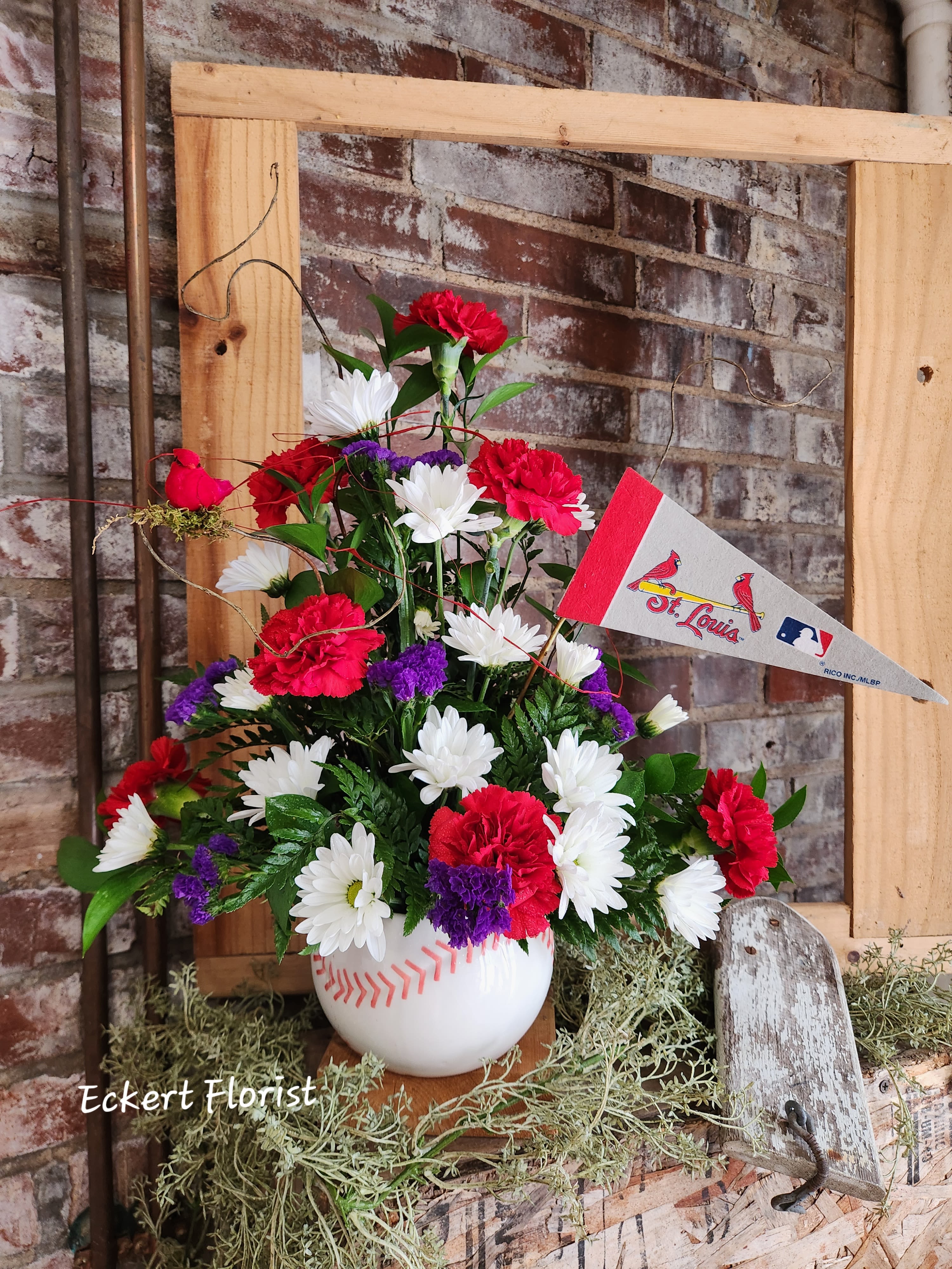 Baseball-themed floral arrangement in a white vase with a St. Louis pennant