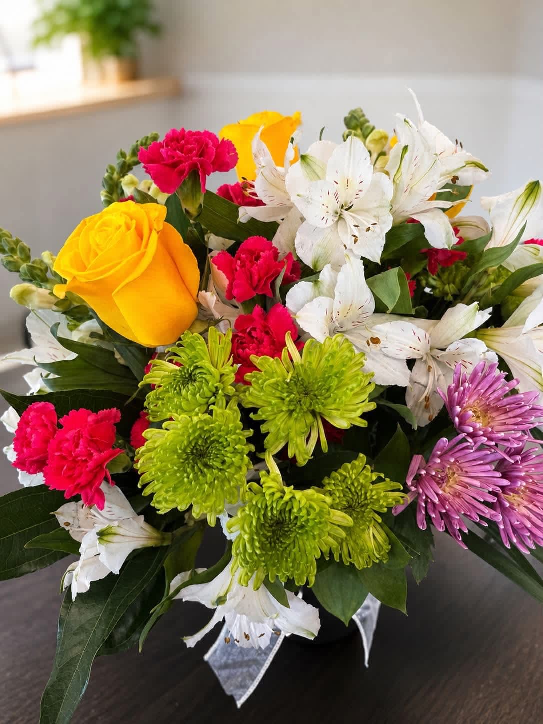 Mixed bouquet with yellow roses, white lilies, pink carnations, and green chrysanthemums