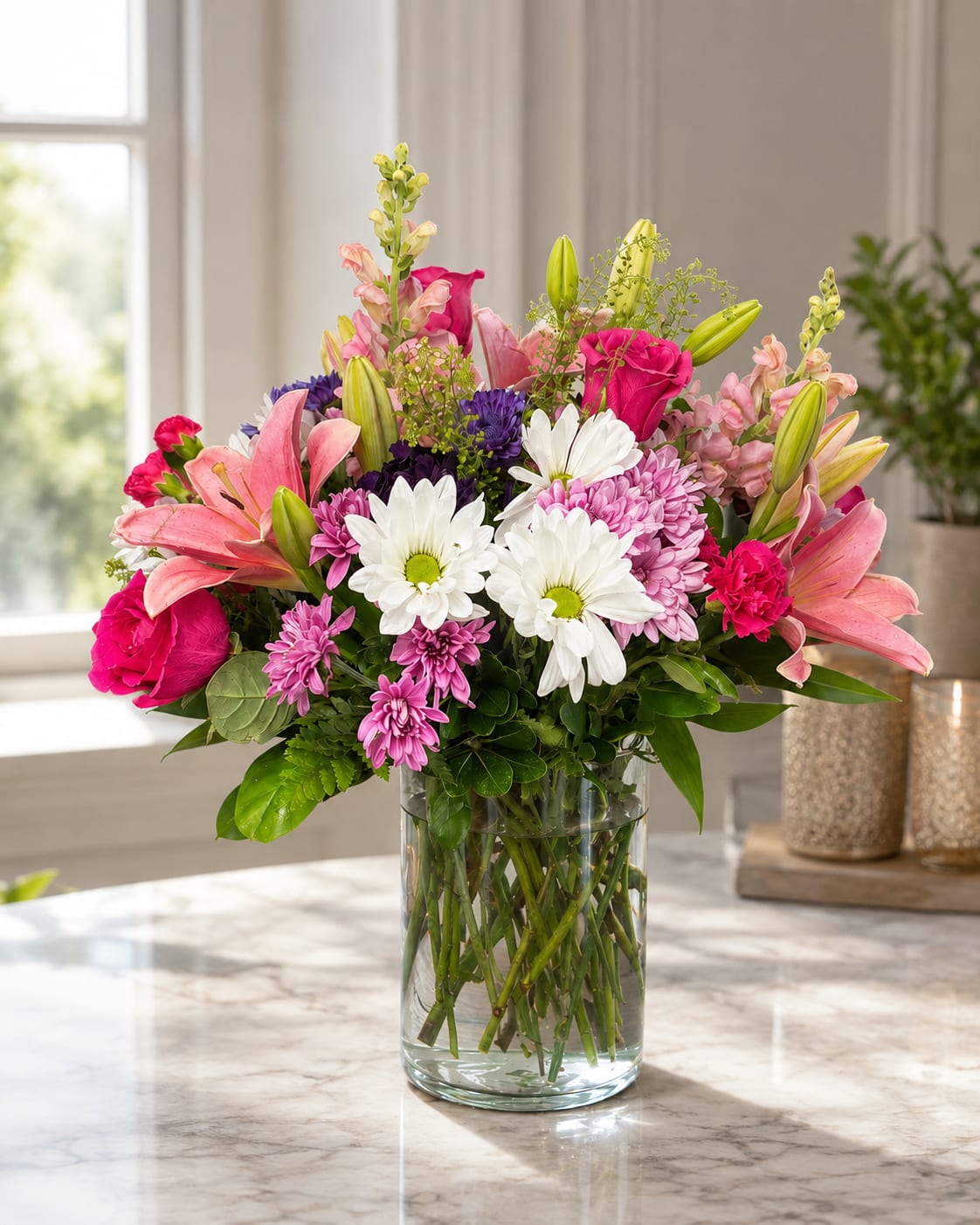 Mixed bouquet of pink lilies, roses, daisies, and purple blooms in a glass vase