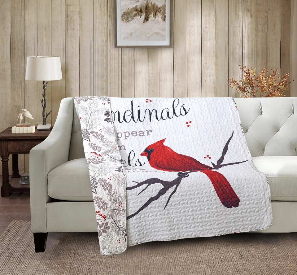 Quilted throw blanket with a red cardinal design draped over a sofa