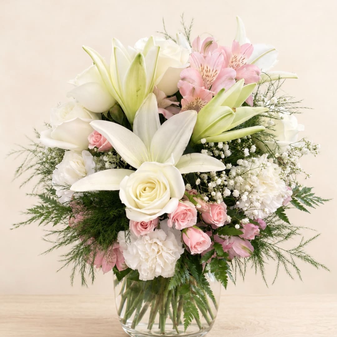 White lilies and roses with pink flowers in a glass vase