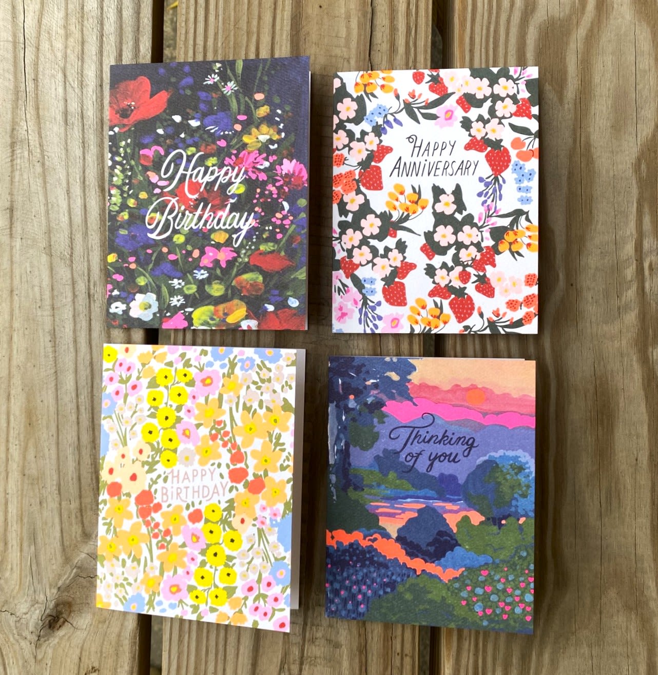 Set of four floral and scenic greeting cards with birthday, anniversary, and thinking of you messages on wood.