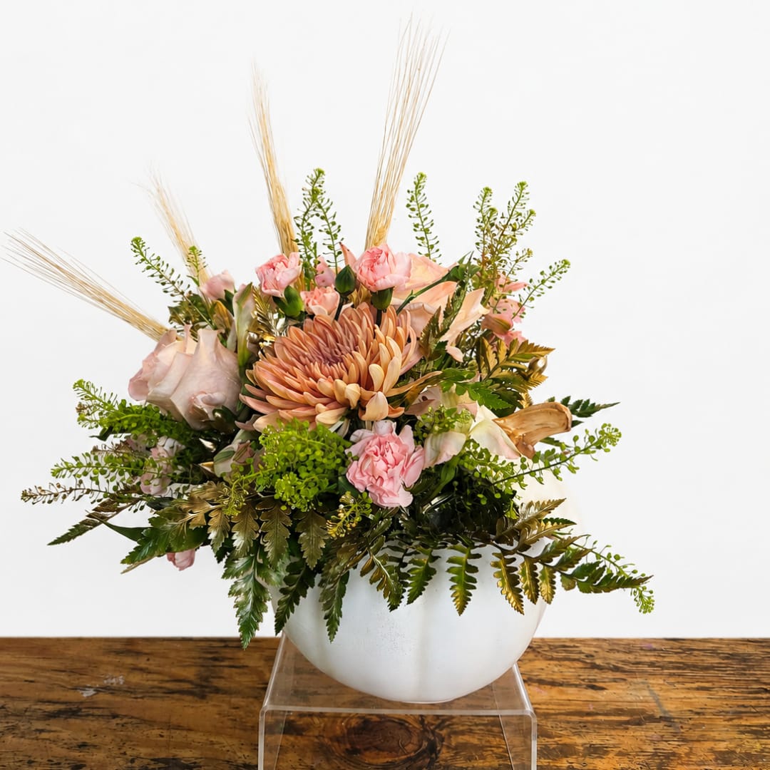Pink and peach floral arrangement in a white bowl vase