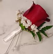 Red rose boutonniere with white filler flowers and green fern leaves