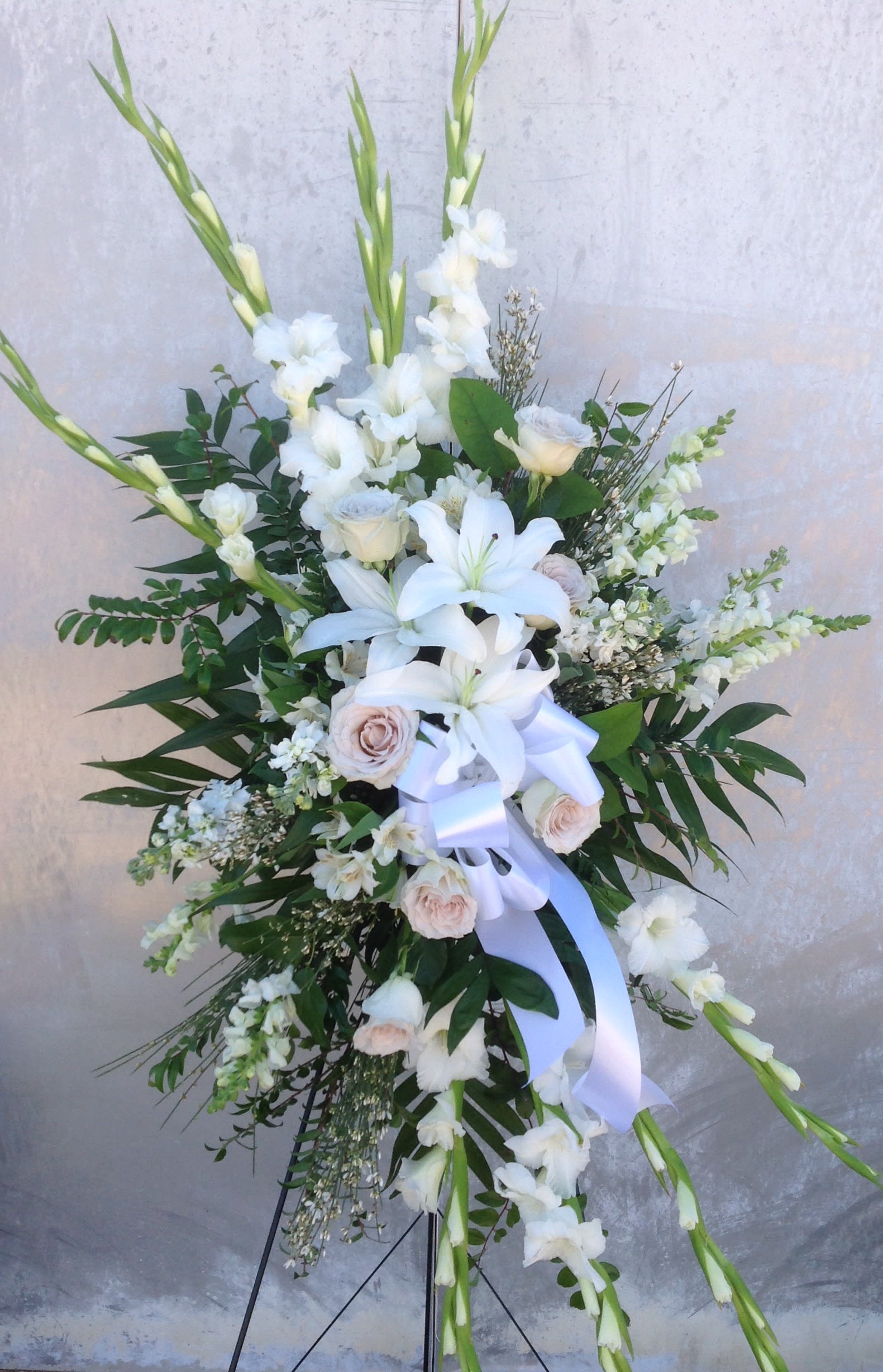 Tall white floral standing spray with lilies and roses on an easel