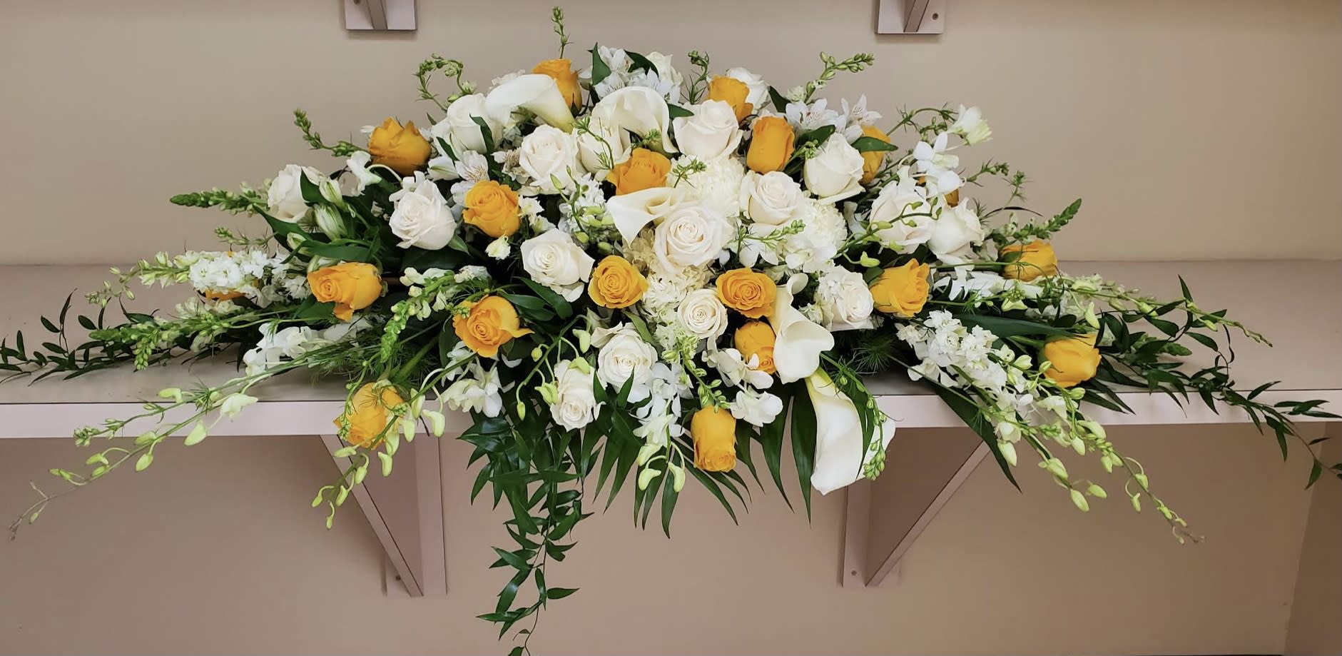 Long floral arrangement of white and yellow roses with white lilies