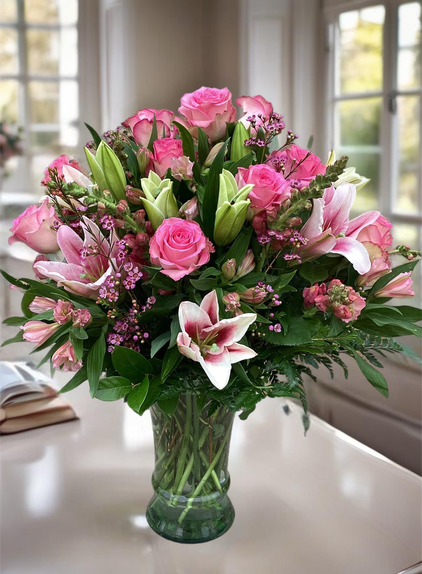 Pink roses and lilies arranged in a glass vase