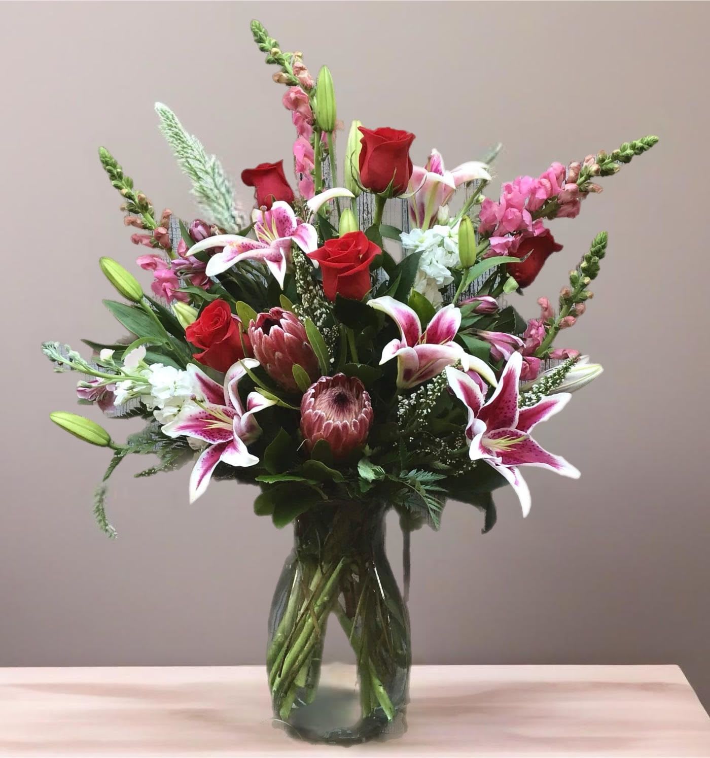 Mixed bouquet of red roses and pink lilies in a glass vase