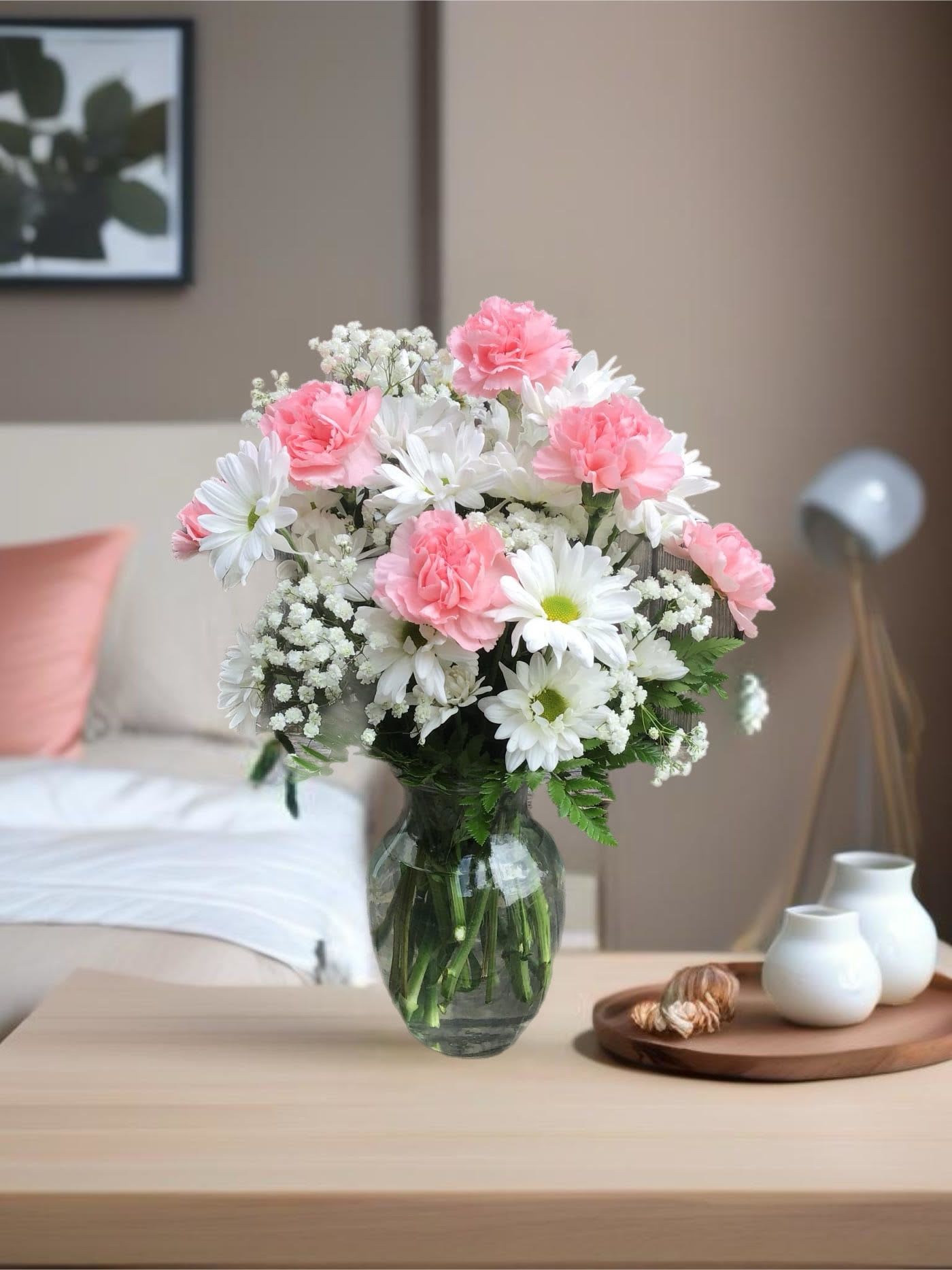 Pink carnations and white daisies in a glass vase