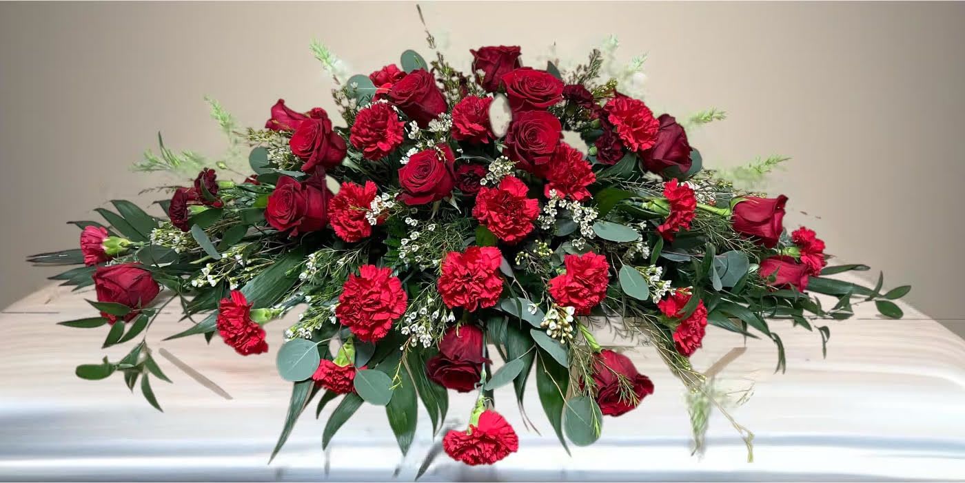 Red roses and carnations arranged in a low casket spray