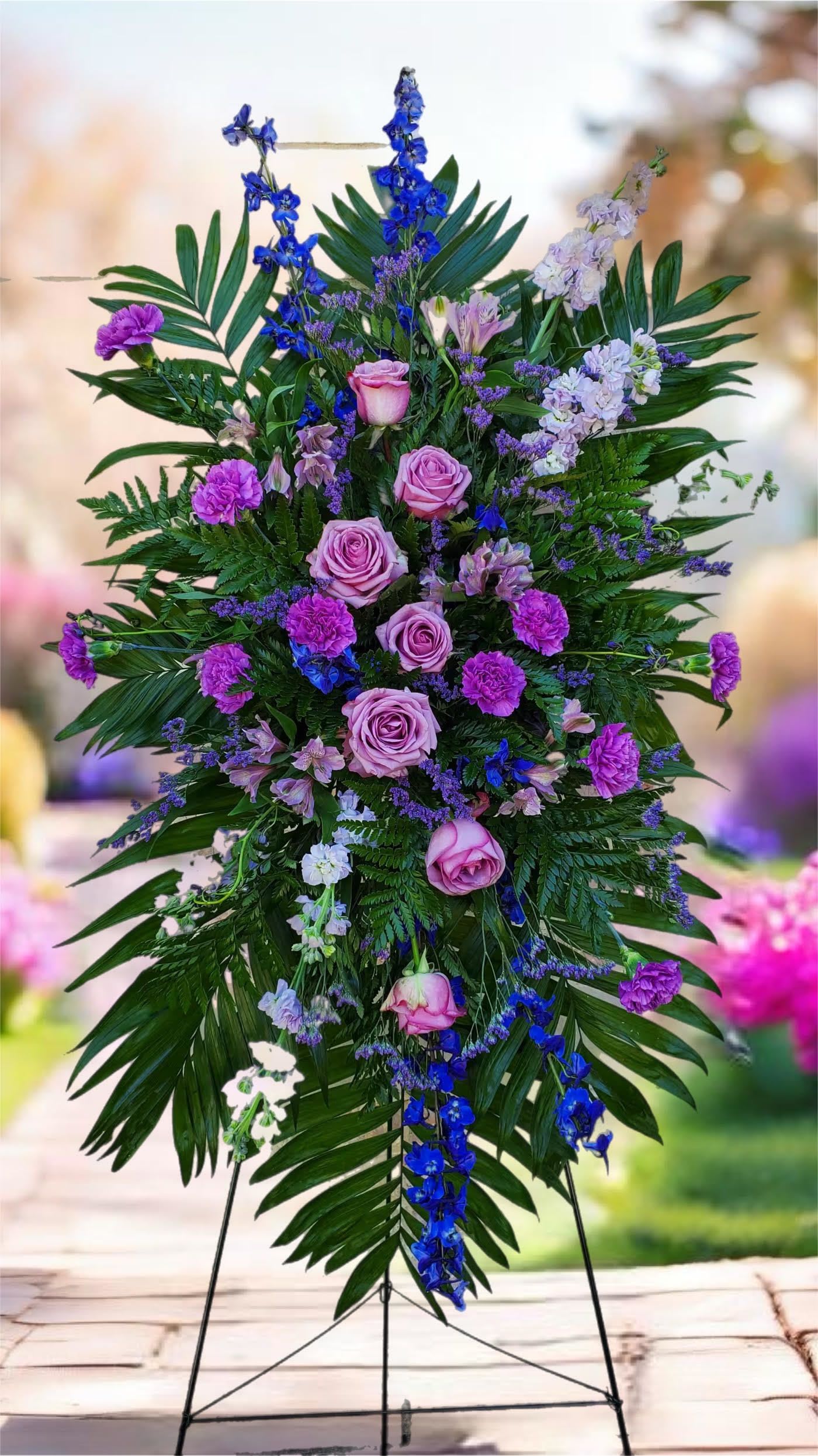 Tall standing floral spray with pink roses and purple blooms on a metal easel