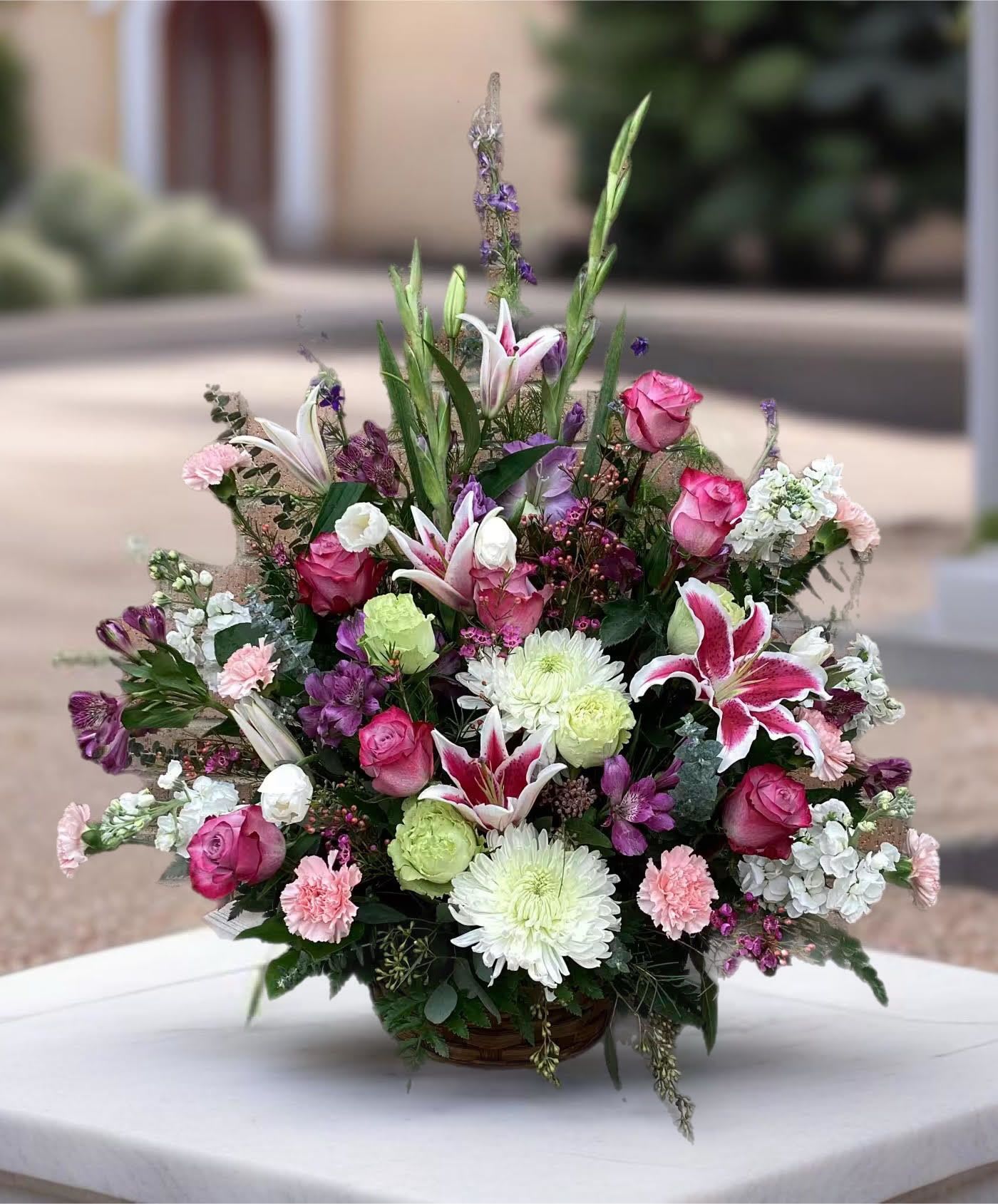 Mixed bouquet in a basket with pink roses, lilies, and white chrysanthemums