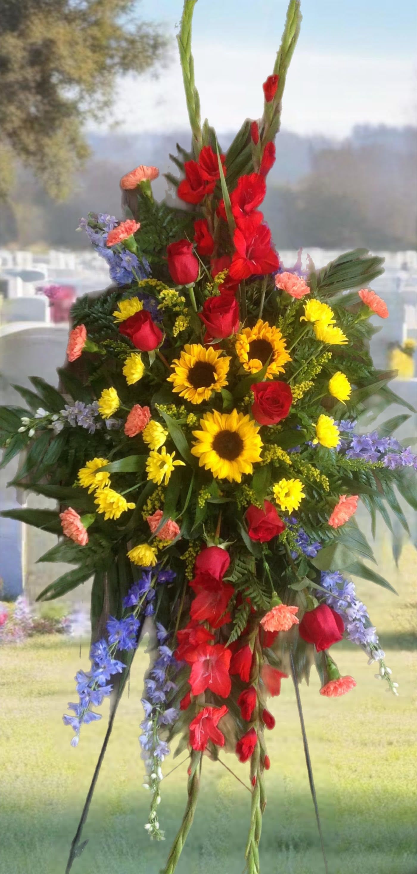 Standing floral spray with red roses, sunflowers, and purple flowers