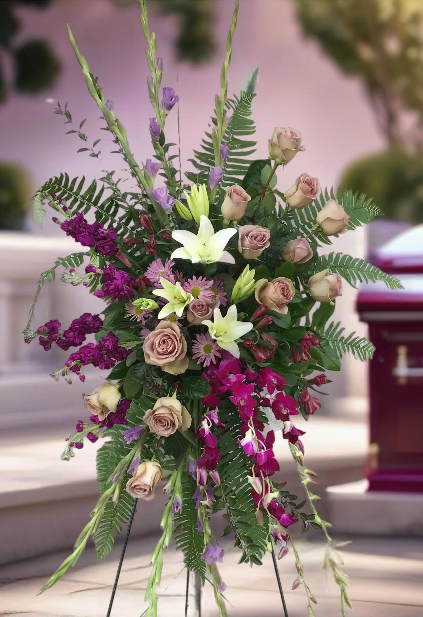 Tall floral spray with roses, lilies, orchids, and purple accents
