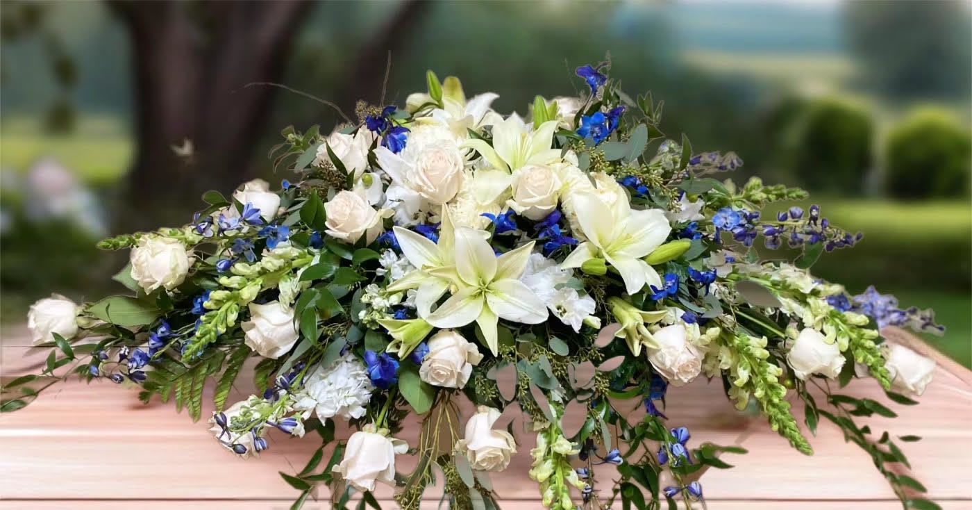 White lilies and roses with blue flowers in a low arrangement