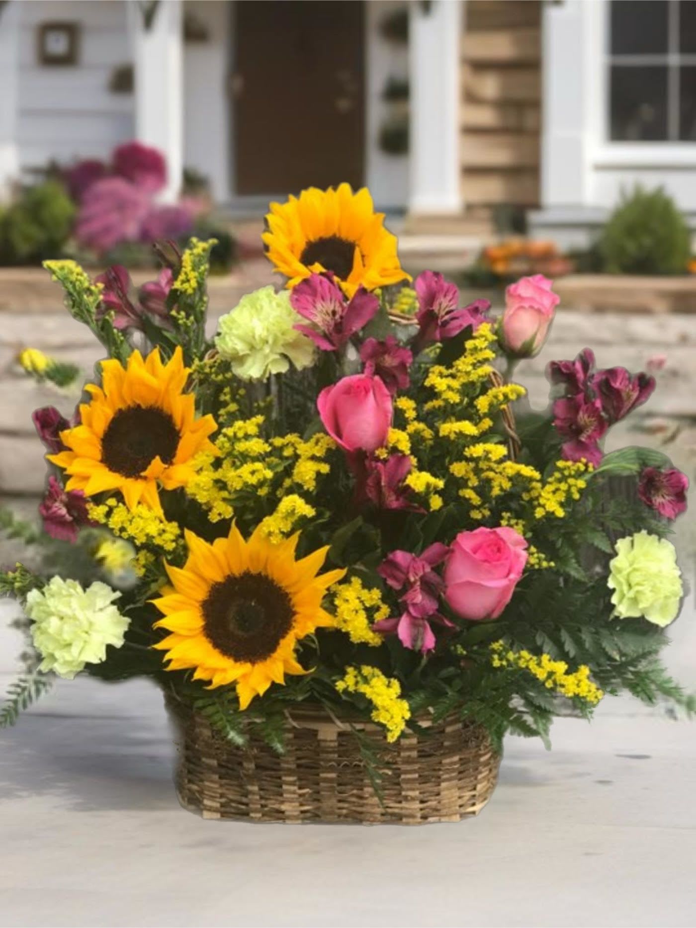 Basket arrangement with sunflowers, pink roses, and yellow filler flowers